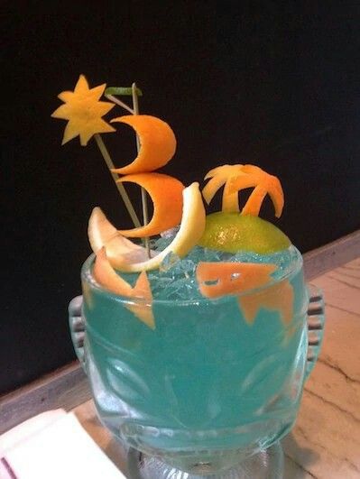 a glass filled with blue liquid and orange slices