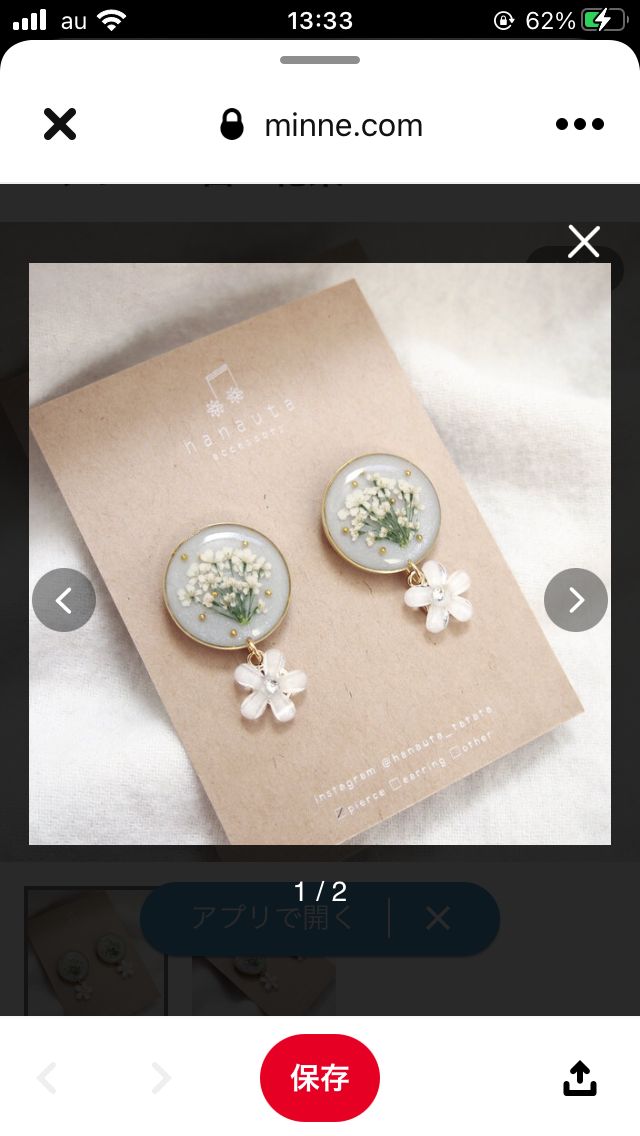 a pair of earrings with white flowers on the front and back of them, sitting on top of a piece of paper