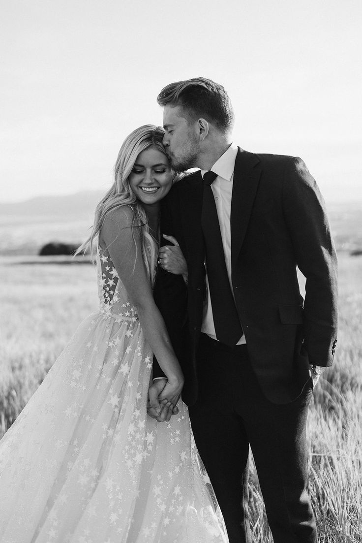 a man in a suit and tie kissing a woman in a wedding dress on the field