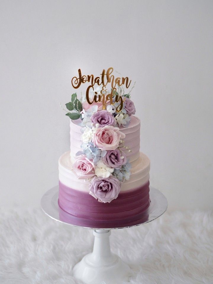 a three tiered cake with flowers on top and the words congratulations cakes written in gold