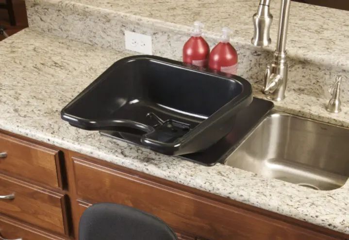 a kitchen sink with a black tray on the bottom and two red balls in the middle