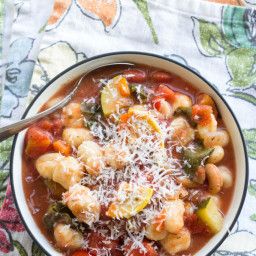 a bowl filled with pasta and vegetables on top of a table next to a spoon