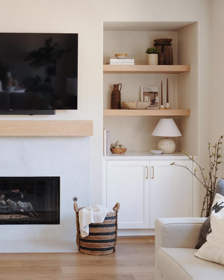 a flat screen tv mounted above a fire place in a living room with white furniture