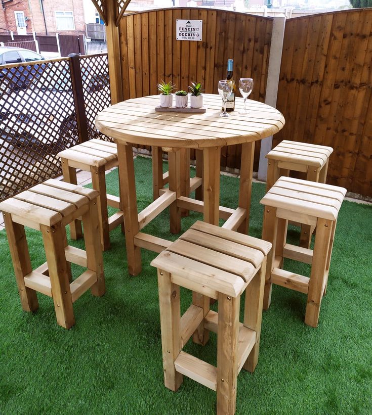 a wooden table and four stools on green grass