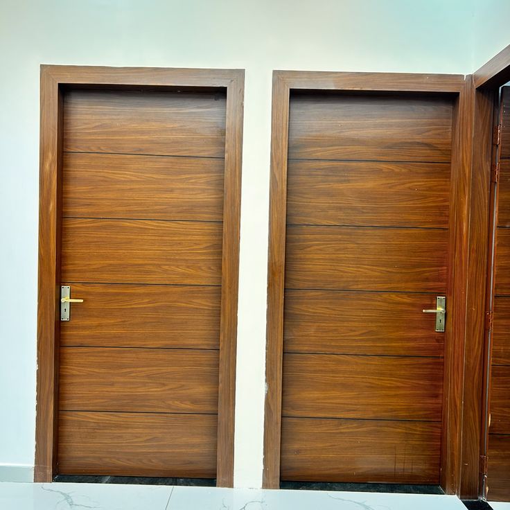 two wooden doors are open in front of a white wall