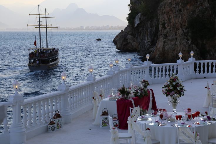 an outdoor dining area overlooking the ocean with a boat in the distance and tables set up for dinner