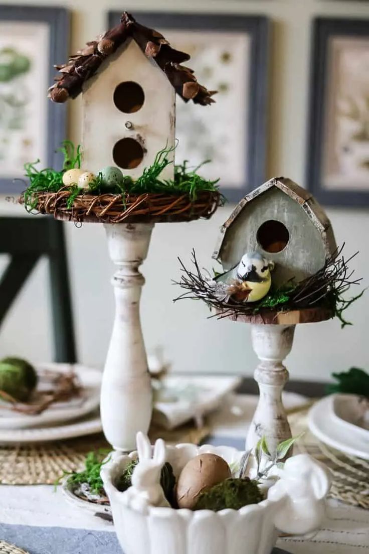 two white bird houses sitting on top of a table next to plates and bowls filled with eggs