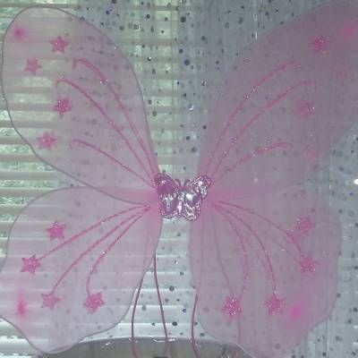 a pink butterfly sitting on top of a window sill next to a white curtain