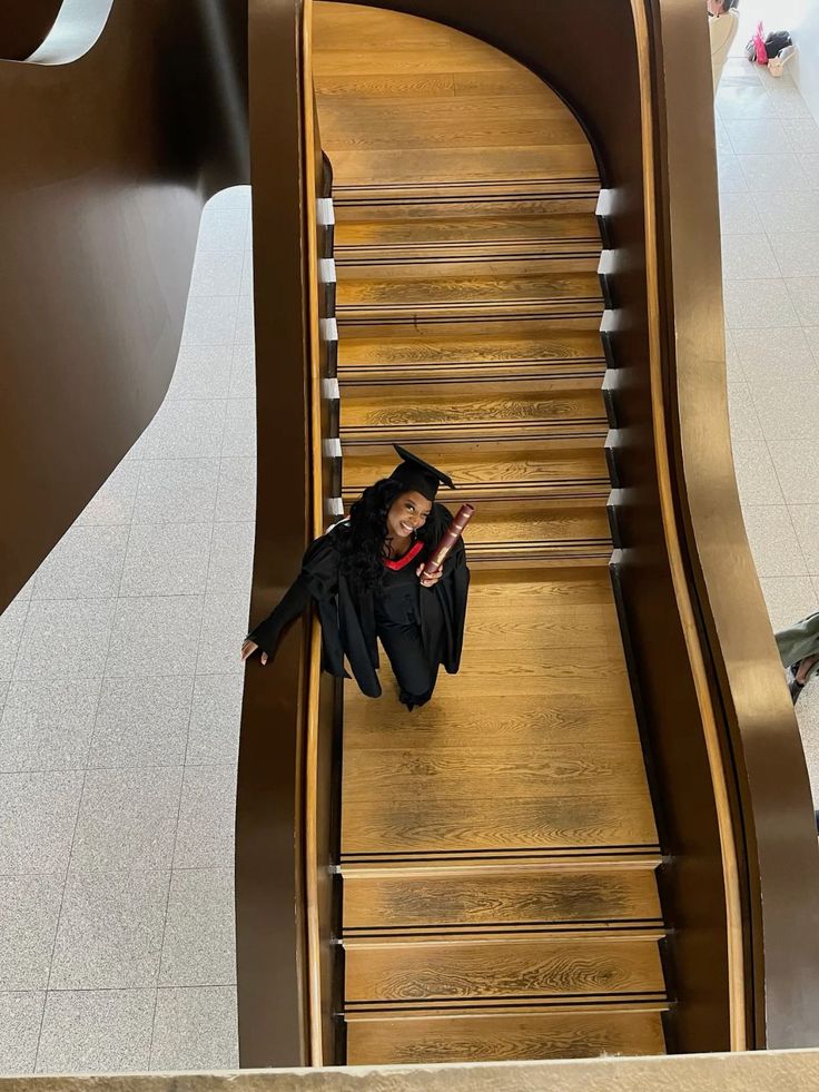 a person laying down on an escalator with a graduation cap and gown over their head