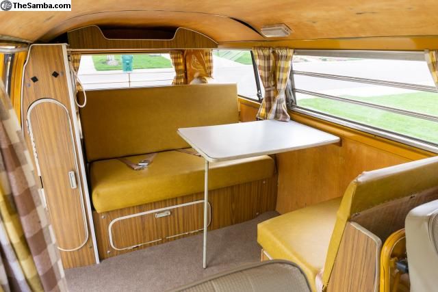 the interior of an old bus with wood paneling and white table, yellow chairs