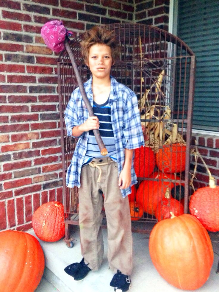 a young boy standing in front of some pumpkins with a broom on his head