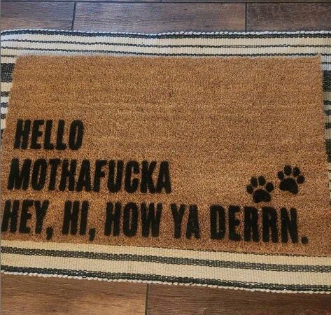 a door mat with the words hello, mothafukka hey, hi, how ya dern on it