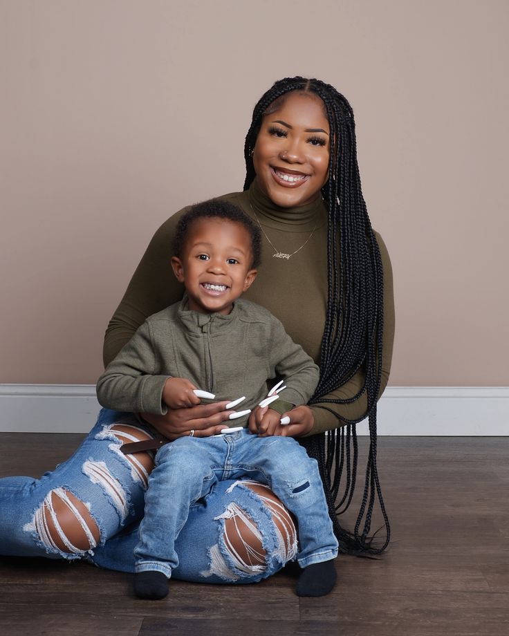 a woman and child sitting on the floor with scissors in their hands, smiling at the camera