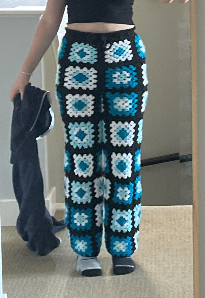 a woman is taking a selfie in the mirror with her cell phone while wearing blue and white crocheted pants