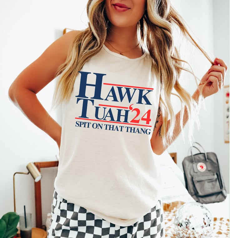 Hawk Tuah 2024 Tee – Vitamin Sea Boutique LLC Cotton Graphic Print Tank Top With Crew Neck, Crew Neck Cotton Printed Tank Top, Cotton Printed Crew Neck Tank Top, Printed Cotton Crew Neck Tank Top, Spring Crew Neck Tank Top With Screen Print, Sleeveless Cotton T-shirt With Printed Design, Relaxed Fit Cotton Graphic Tank Top, Sleeveless Cotton T-shirt With Print, Cotton Tops With Letter Print For Summer