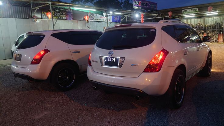 two white suvs parked next to each other in front of a building at night