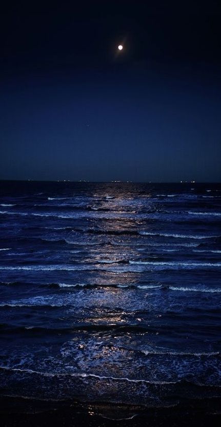 the moon is shining over the ocean at night