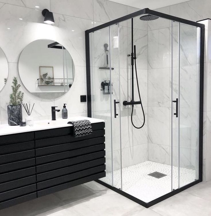 a modern bathroom with black and white fixtures, marble counter tops, and an open shower