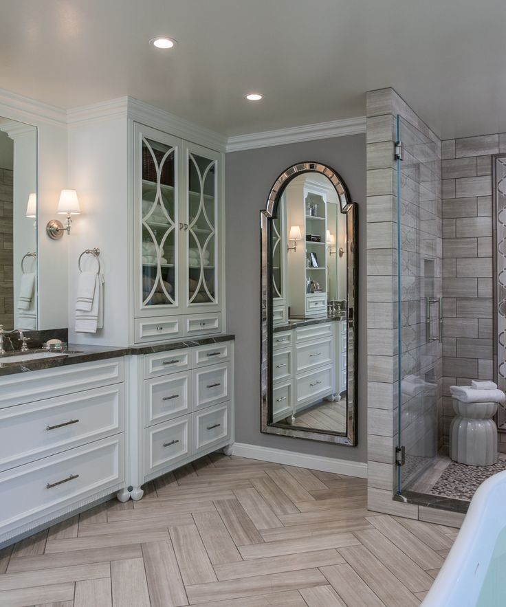 a large bathroom with white cabinets and marble counter tops