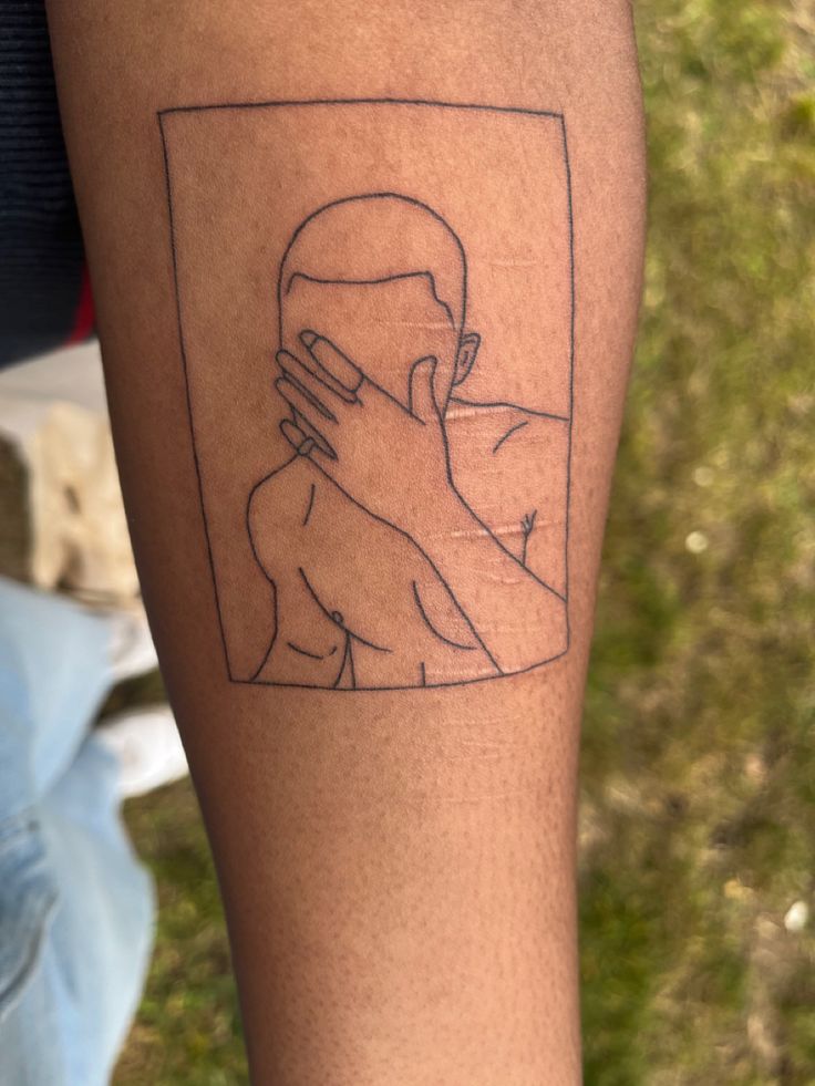 a man's arm with a drawing of a person holding his face in front of him