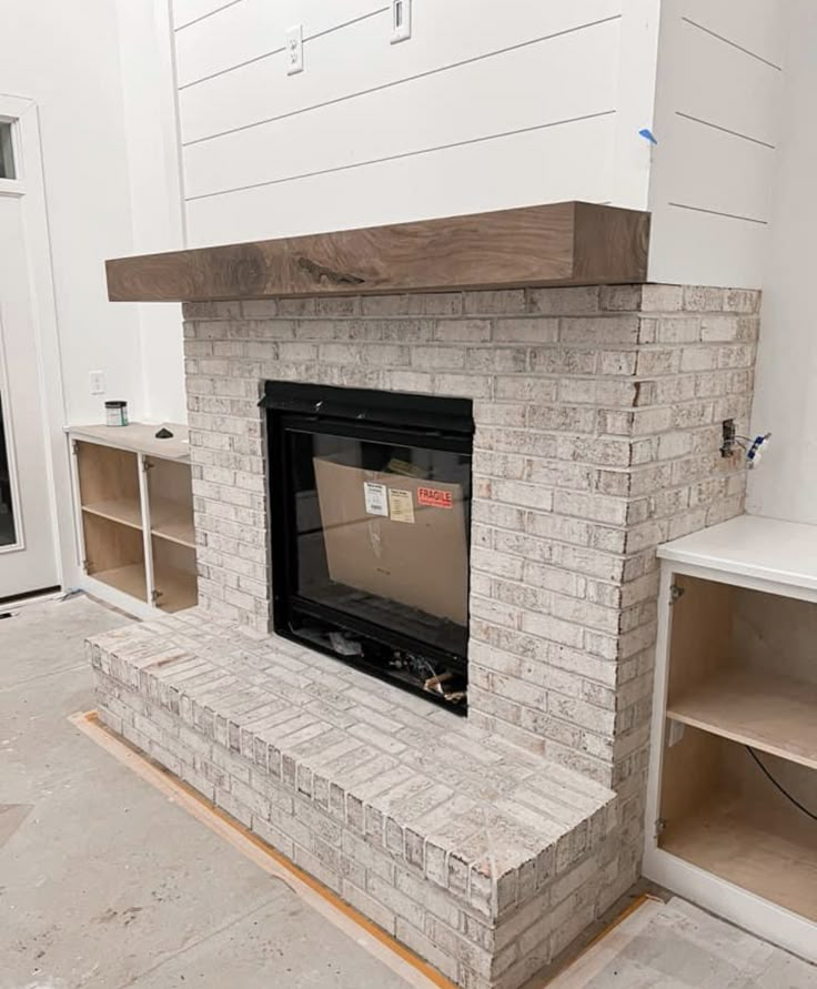 the fireplace is being installed in the living room with white cabinets and shelvings