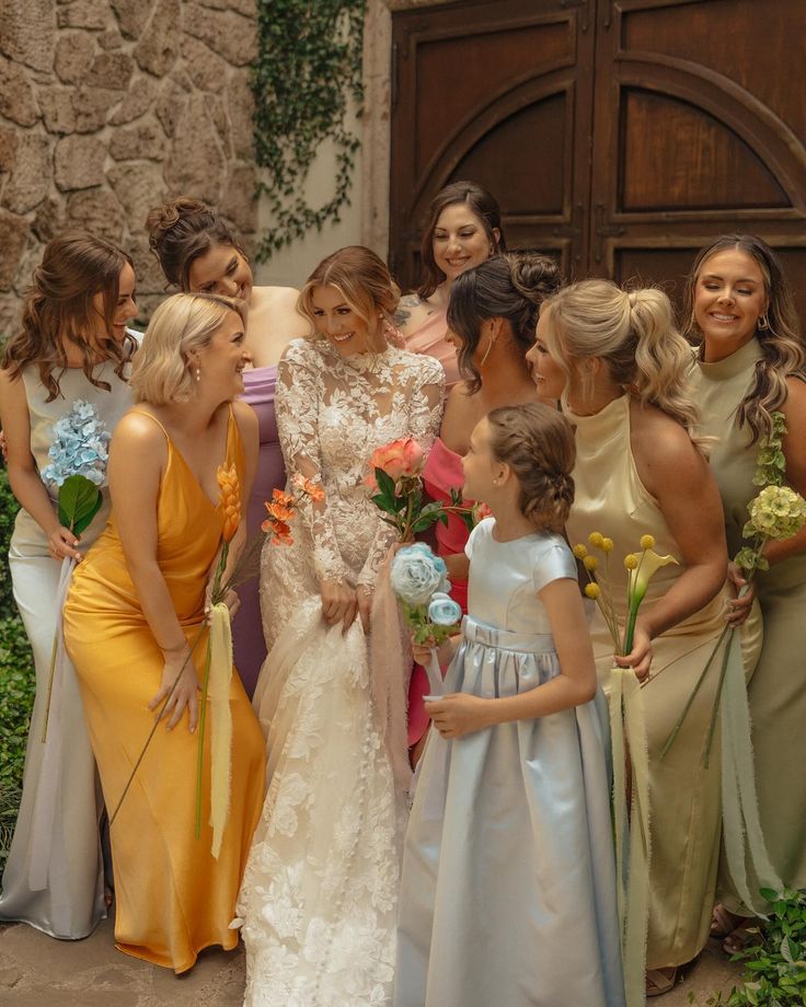 a group of women standing next to each other in front of a stone wall and door