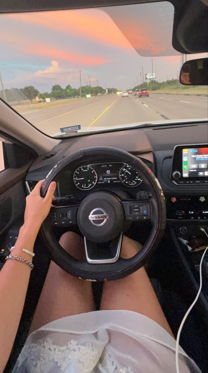 a woman is driving her car on the road