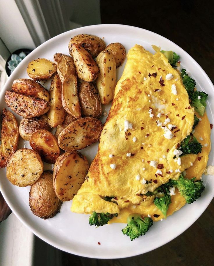 an omelet, potatoes and broccoli on a white plate