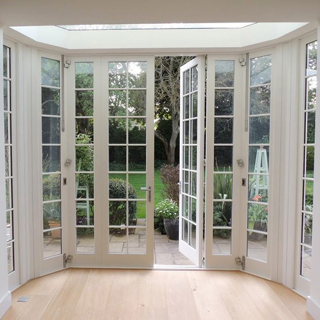 an empty room with french doors leading to a garden and trees in the back ground