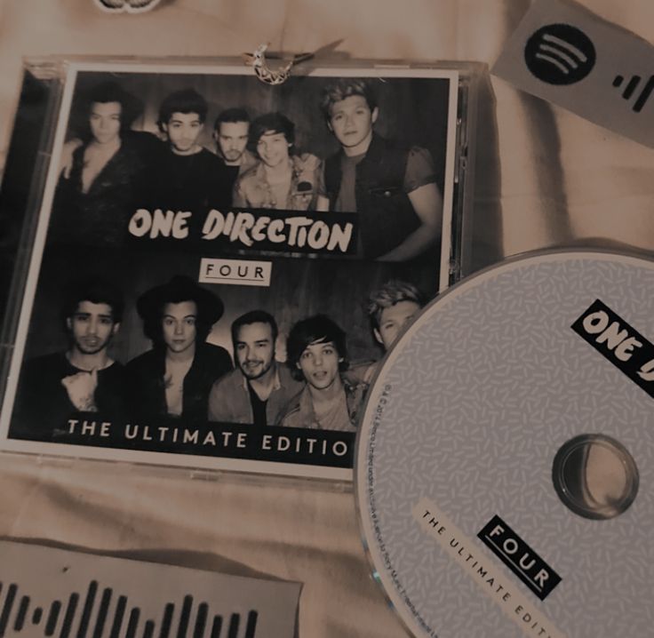 the one direction tour dvd and disc are laying on top of a bed with other items