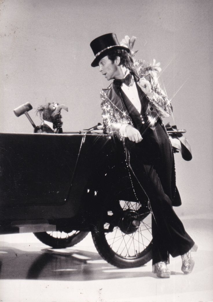 a man in top hat and tails riding on the back of a car