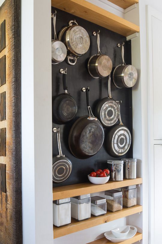 an organized kitchen with pots and pans hanging on the wall