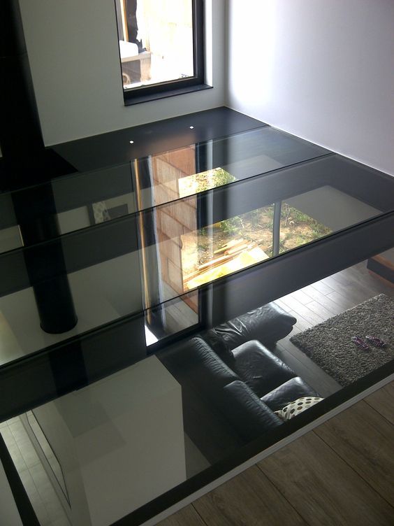 a living room with a couch and glass shelves on the wall next to a window