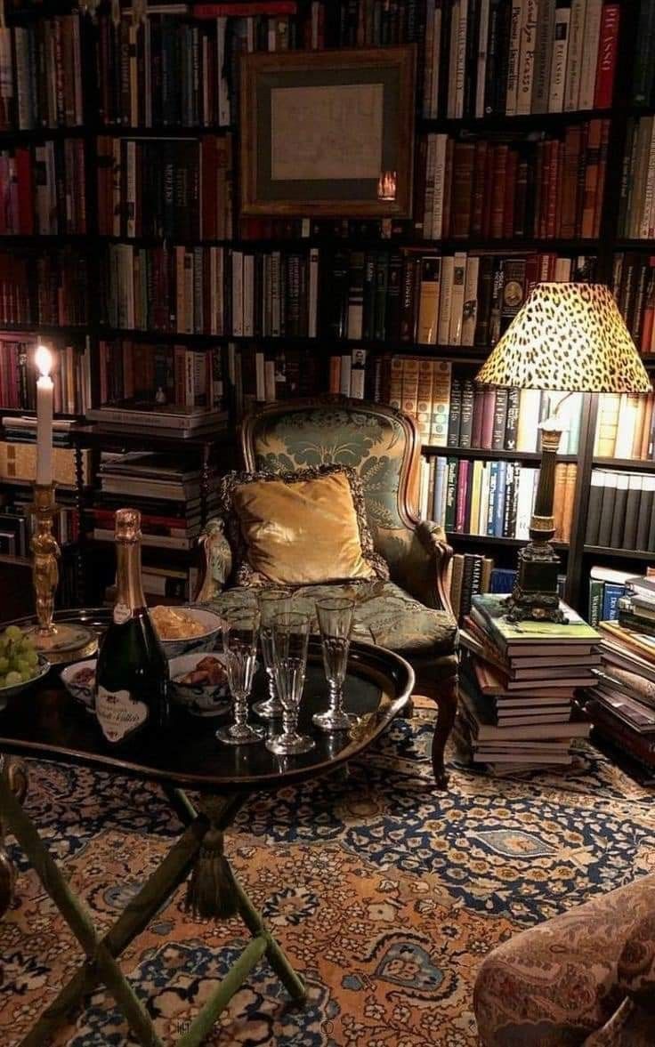 a living room filled with lots of books and wine glasses on top of a table