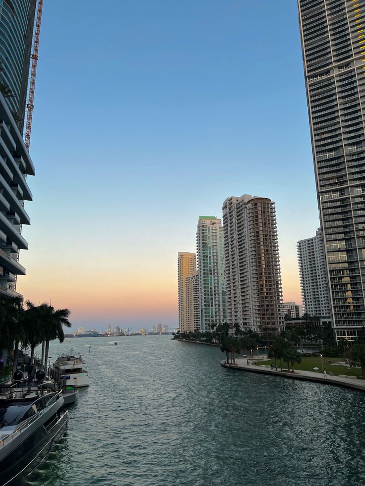 boats are parked along the water in front of high rise buildings and skyscrapers at sunset