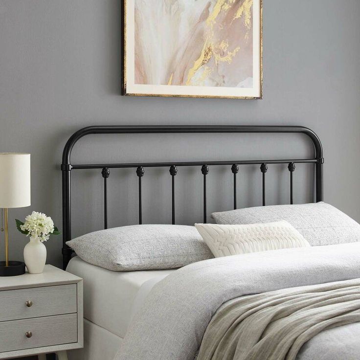 a bedroom with gray walls and white bedding has a painting on the wall above it