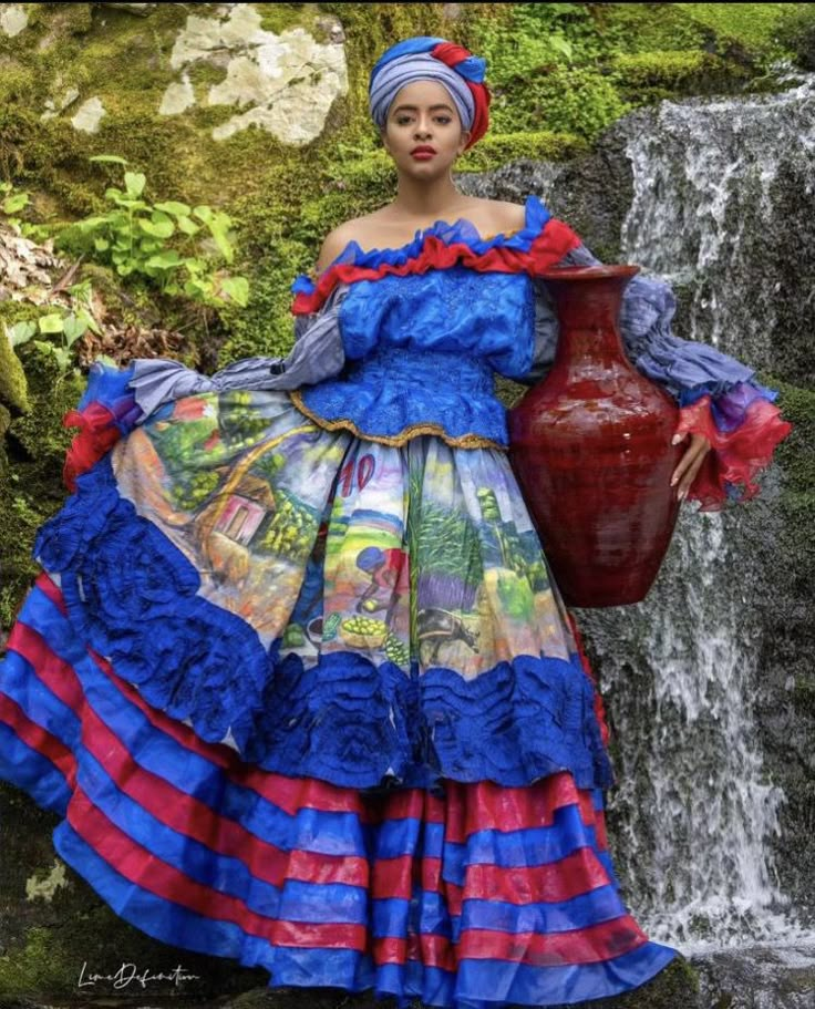 a woman in a blue and red dress standing next to a waterfall with a vase