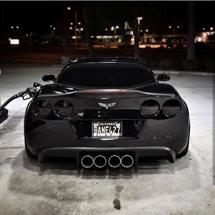 a black sports car parked in a parking lot with its hood up and exhaust pipe out