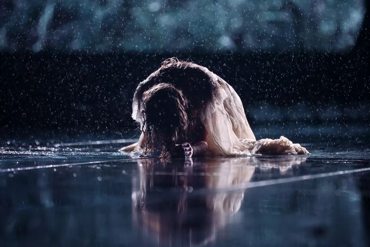 a woman is laying down in the rain with her head on her knees and hands behind her back