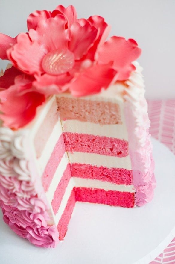 a pink and white cake with flowers on top