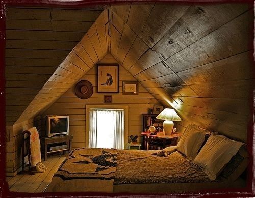 an attic bedroom with a bed and television in the corner, along with pictures on the wall