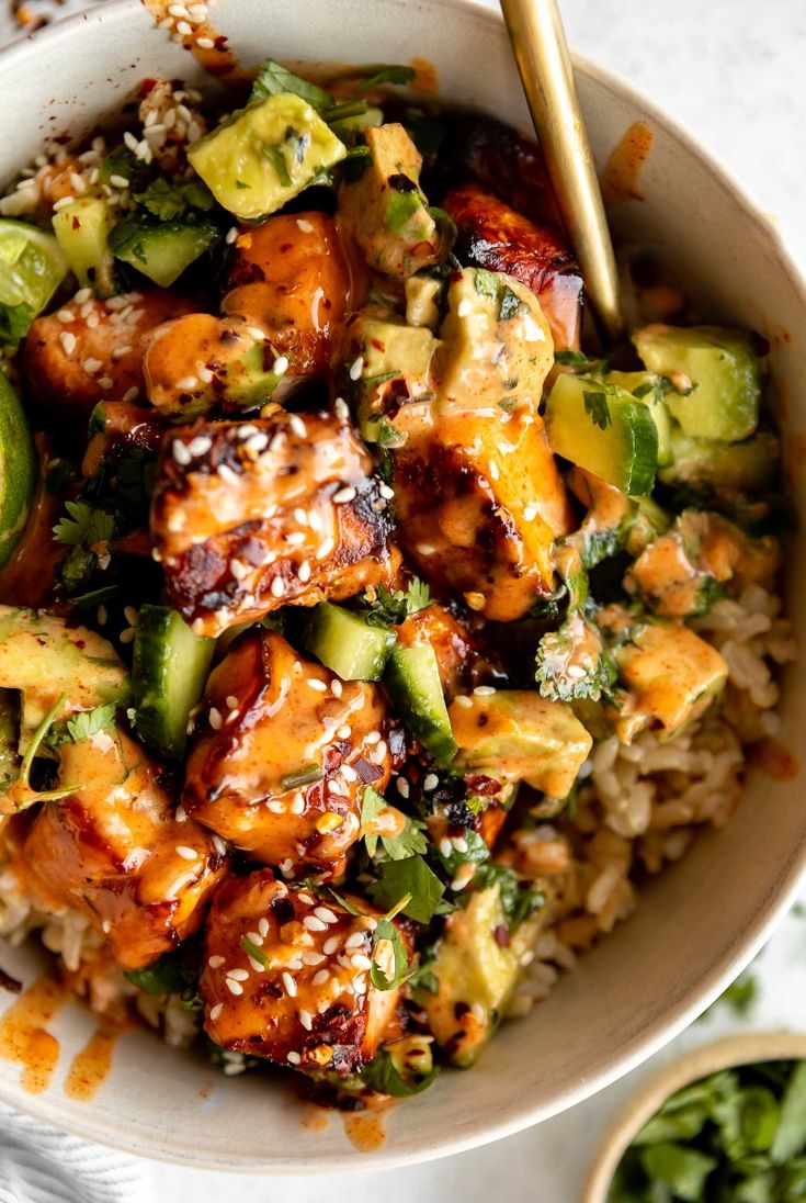 a white bowl filled with chicken and vegetables on top of rice next to chopsticks