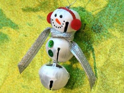 a snowman ornament is hanging from a string on a yellow background with green grass