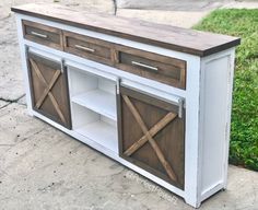 a white and brown cabinet sitting on top of a cement floor next to grass with wooden doors