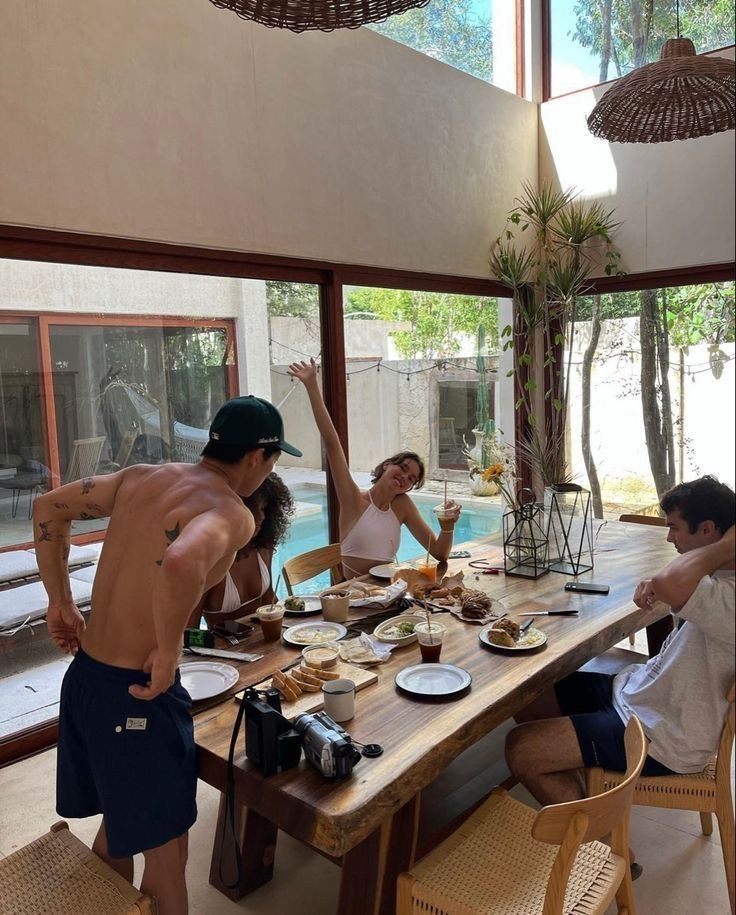 a group of people sitting around a table with food and drinks in front of them