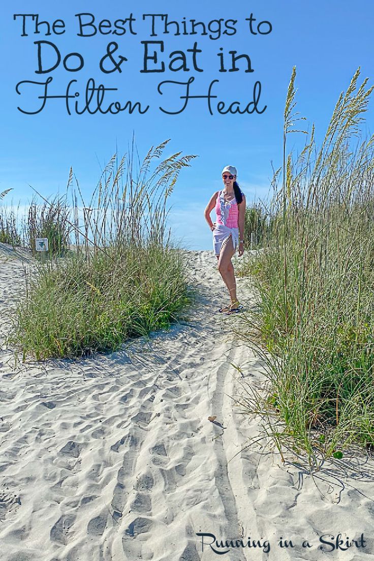 a woman standing on top of a sandy beach next to tall grass and sea oats