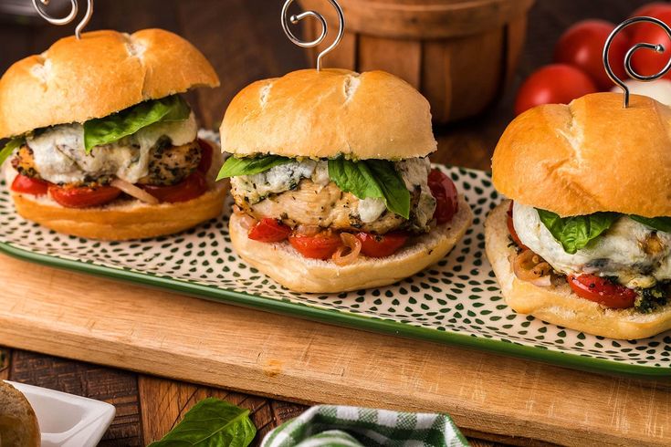 three sandwiches on buns with meat and veggies in the middle, sitting on a tray