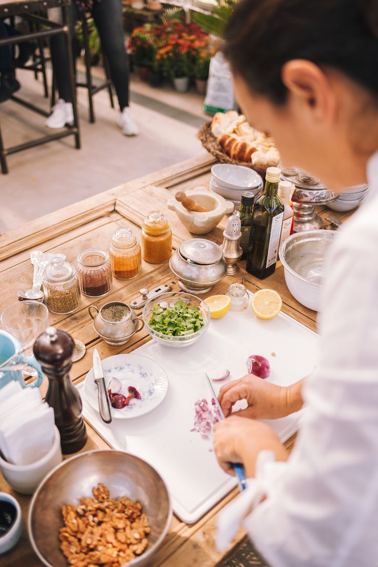 a woman is preparing food on a table with bowls and utensils in front of her