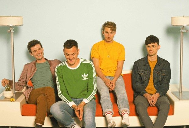 four young men sitting on a red couch