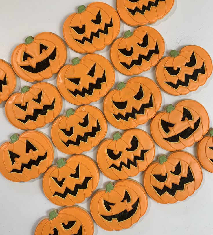 a pile of pumpkin shaped cookies sitting on top of a white table next to each other